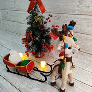 Reindeer with a sleigh a bag for gifts and Christmas tree